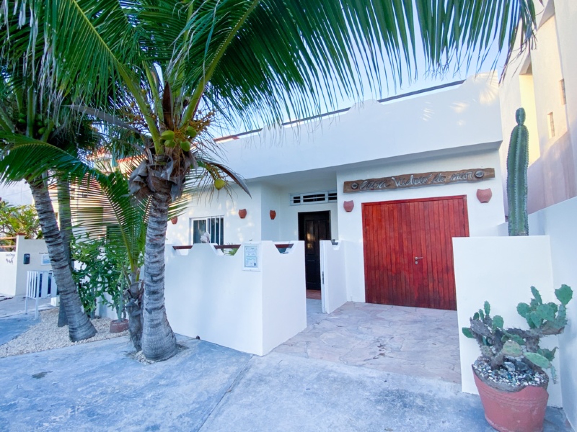 Front entrance with red door and palm trees — Rincón del Descanso Isla Mujeres