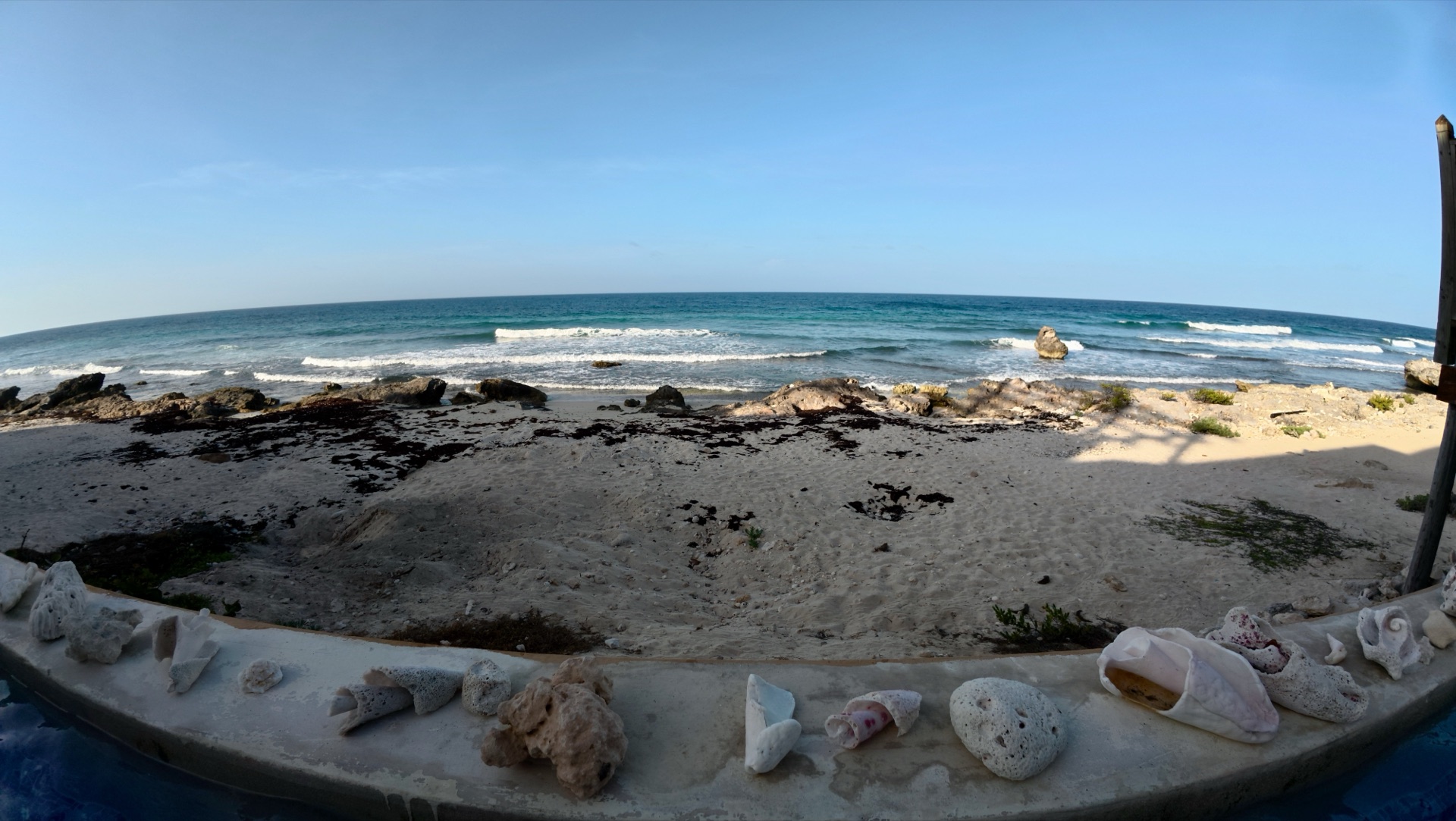 Beach view from the pool ledge lined with shells Isla Mujeres