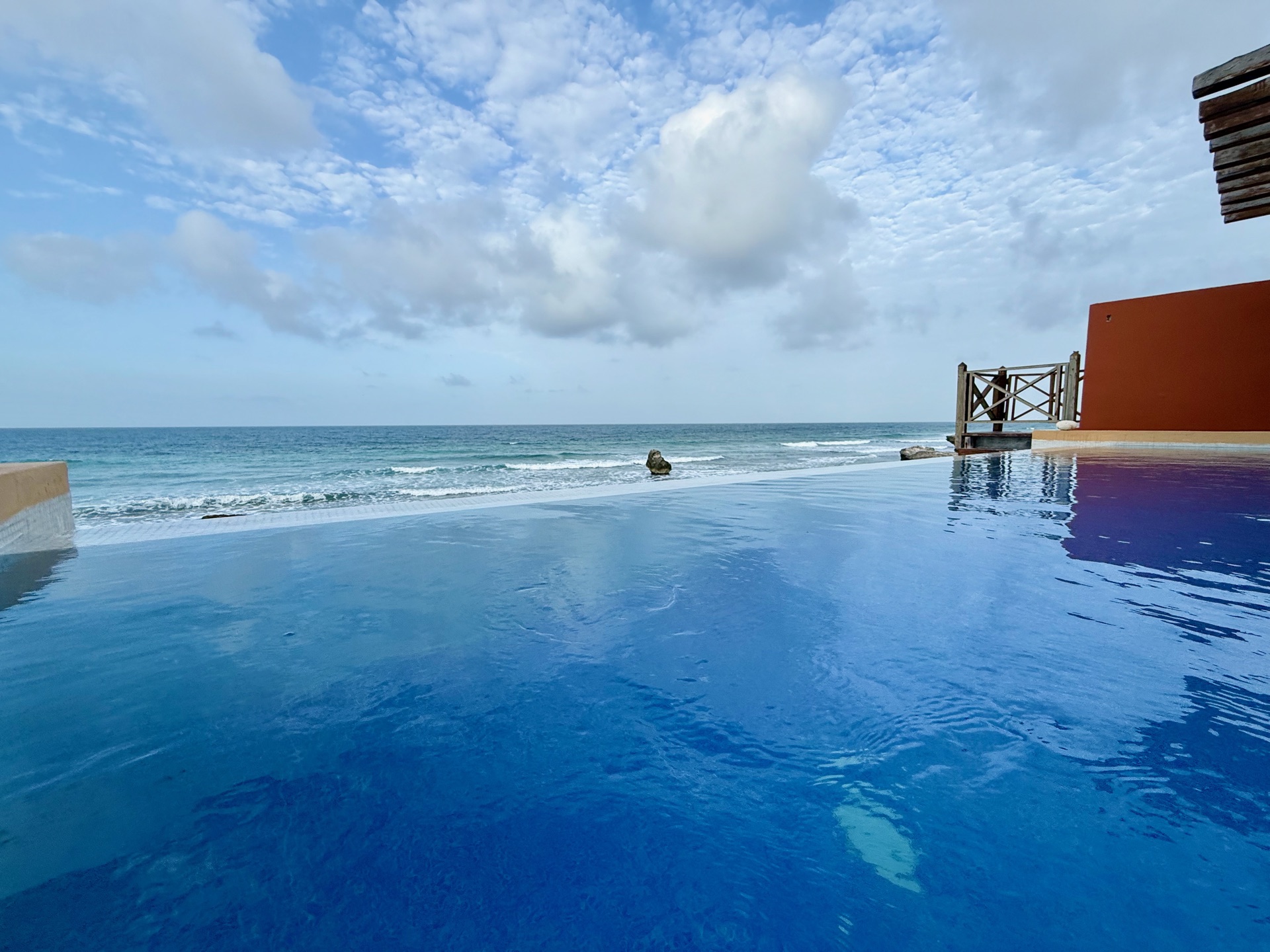 Infinity pool terrace at dusk with terra cotta wall — Rincón del Descanso Isla Mujeres