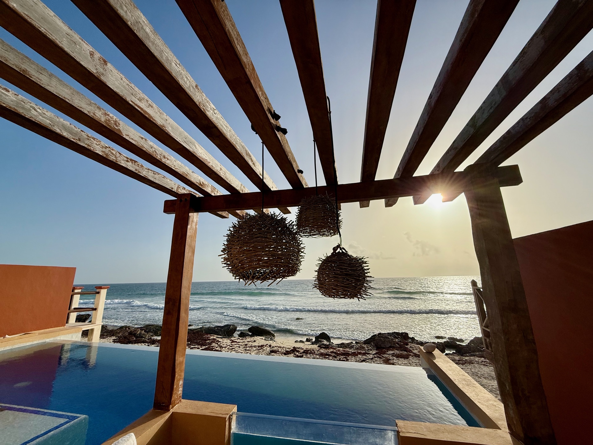 Pergola with woven pendant lights over the infinity pool at sunset Isla Mujeres